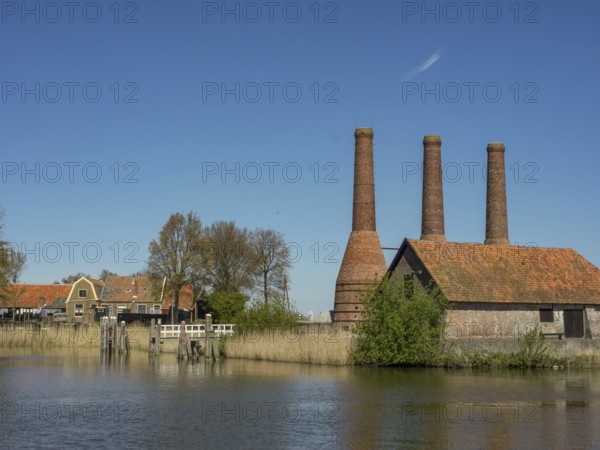 Old factory site with three tall chimneys on the waterfront, enkhuizen, the netherlands