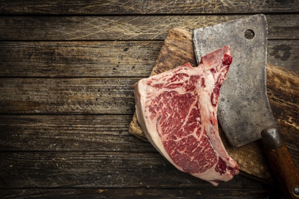 Raw fresh meat T-bone beef Steak and butcher knife on wooden background, top view
