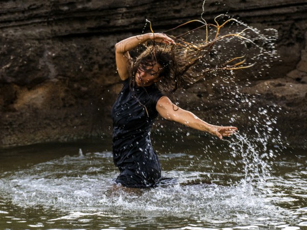 Middle-aged woman dancing and throwing water in the air, Maioris beach, llucmajor, Majorca, Balearic Islands, Spain