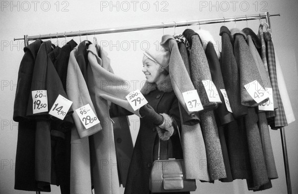 Great discounts of outerwear in the 1960s. A woman stands by a clothes rack, choosing from outerwear and coats marked with price tags with discounted prices. Judging by her face, she appreciates the reduced prices and thinks she's getting real bargains. Sweden January 1963. Ref CV28