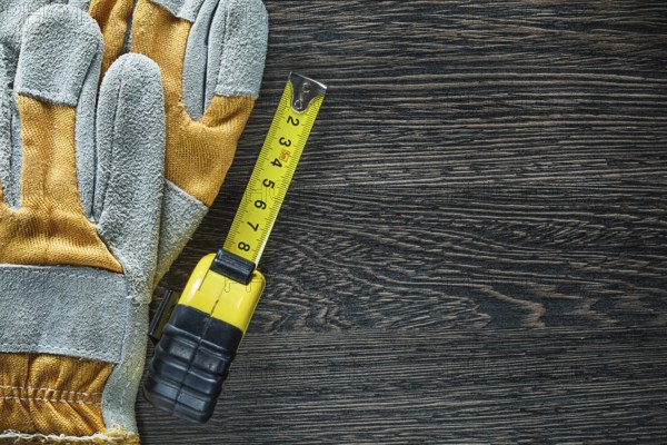Rolled tape measure safety gloves on wood board