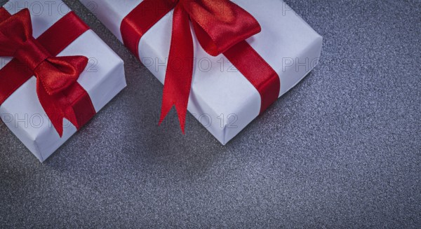 White giftboxes with red knots on grey surface holidays concept