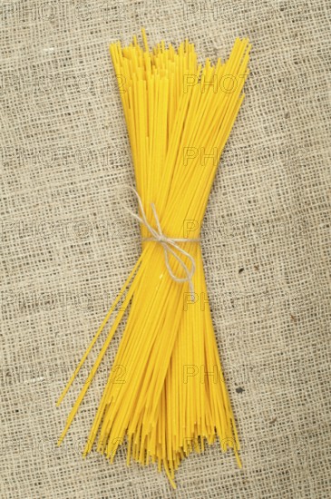 Bundle of spaghetti on burlap brown background