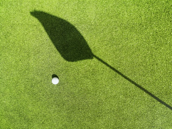 Golf ball on the green, shadow of a flag on a green, golf course