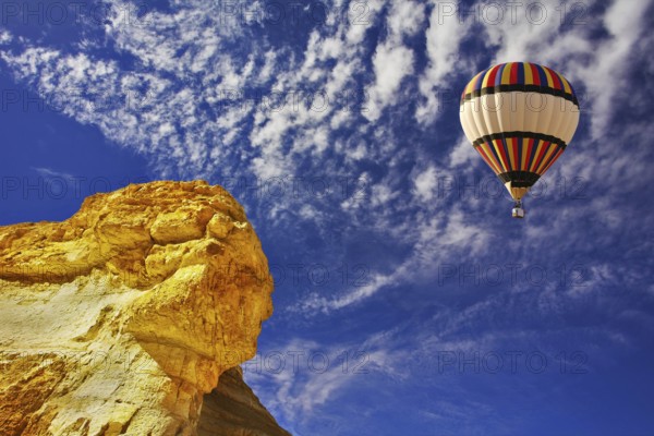 The bright decorative balloon flies above stone desert