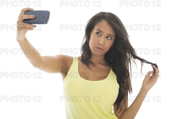 Young attractive black woman is taking a selfie with her cellphone isolated over white background