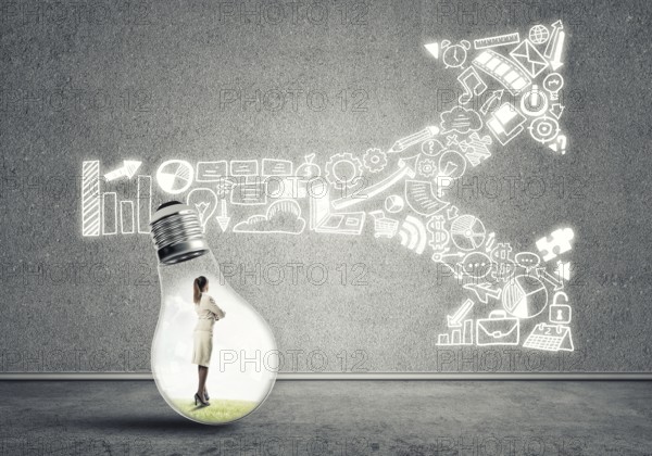 Businesswoman inside of light bulb in empty concrete room