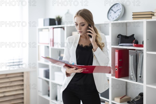 Beautiful young girl with blond hair in a white jacket and black blouse is working in the office. photo with depth of field