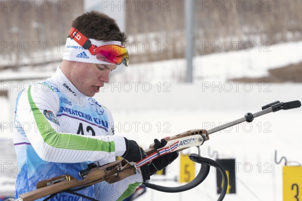 Biathlete reloads rifle before rifle shooting on shooting range. Sportsman biathlete Zlobin Vladislav Khanty-Mansiysk. Regional youth biathlon competitions East Cup. Kamchatka, Russia, April 12, 2019
