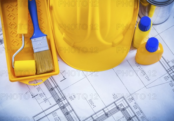 Building helmet paint brush roller tray bottles and can on blueprint construction concept
