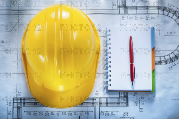 Protective building helmet notebook pen on blueprint