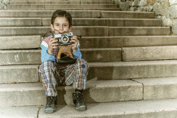 Child with vintage camera. Exterior stairs