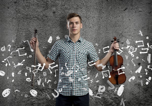 Young handsome guy on cement background with violin