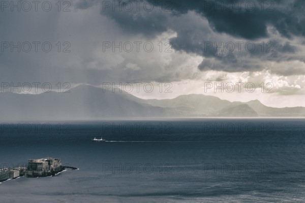 Amazing aerial filtered view of the Gulf of Naples. Fortress Castel del Ovo at the bottom left point. The ship is sailing to Naples. and the southern part of the bay in the distance. Fantastic dramatic sky