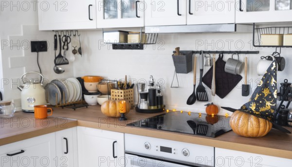 Decor of the white classic kitchen with pumpkins for Halloween and harvest. Autumn mood in the home interior, modern loft style