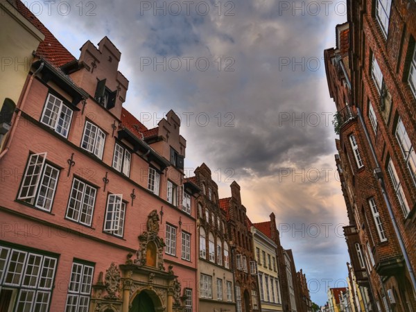 View of historic house facades in a narrow street under a dramatic sky, lübeck, schleswig-holstein, germany