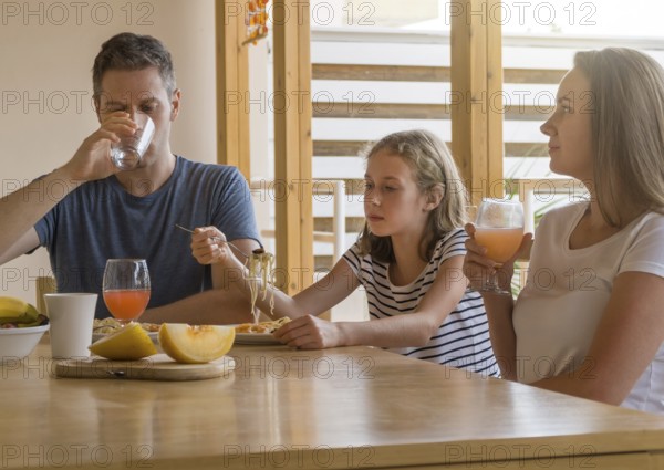 Dad, mom and their daughter have lunch outdoors