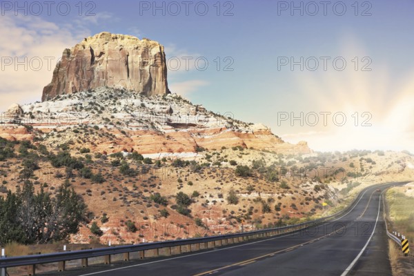 Gorgeous American Highway. Monument Valley in Utah on a cloudy windy day. Shining rays of evening sun sharp light the way