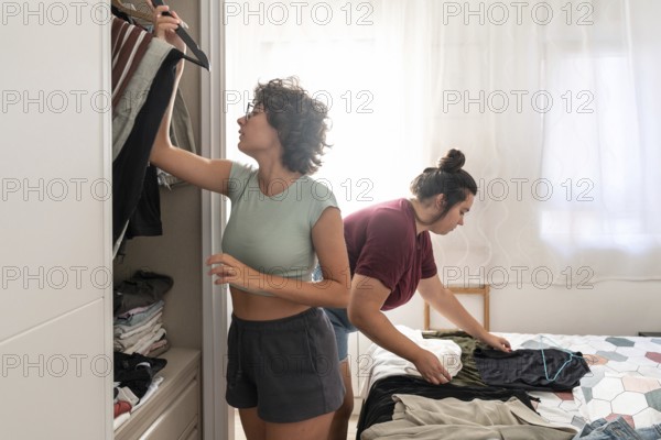A joyful couple shares a playful moment together in a cozy bedroom, with sunlight filtering through white curtains, capturing warmth and happiness