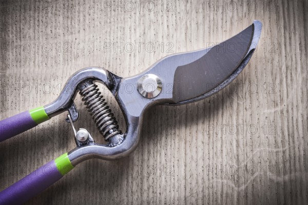 Sharp metal pruning shears on wooden board agriculture concept
