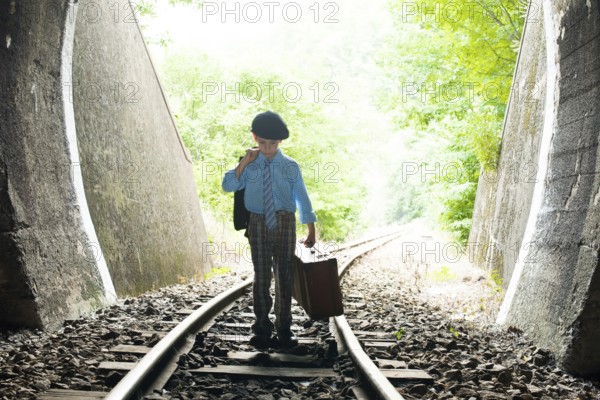 Child walking on railway road with vintage siutcase