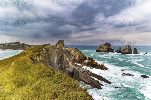 Rocky coastline of the Atlantic Ocean. Spanish coast, Cantabria. Portio beach. Stormy autumn day in the Bay of Biscay. Picturesque cliffs and huge stones oppose the ocean