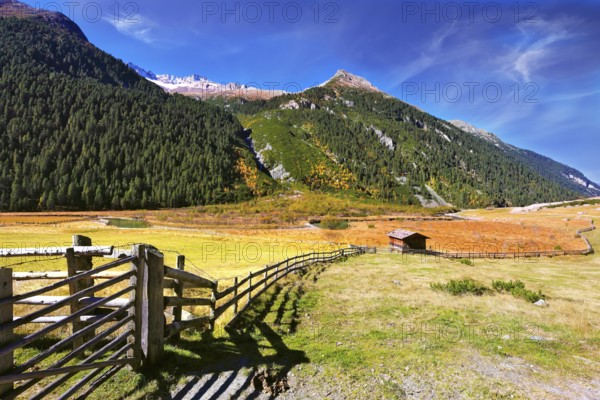 The beautiful autumn day in the Austrian Alps. Farmers alpine meadows blocked by low wooden fences