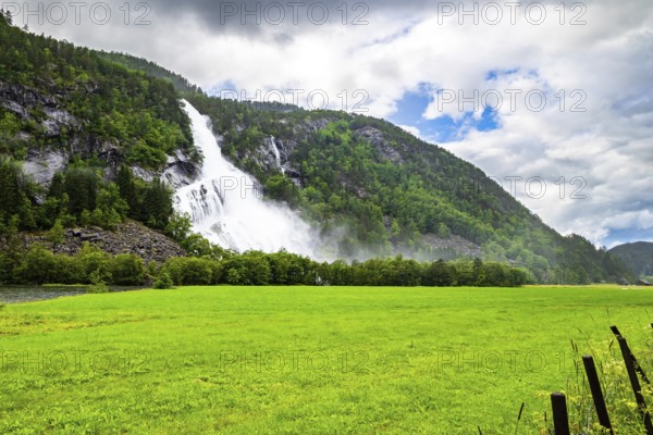 Norway. Huge powerful cascading waterfal Vidfossen. Scenic road in the mountains of Western Norway. White water foam envelops the foot of the waterfall. Scandinavia. Summer