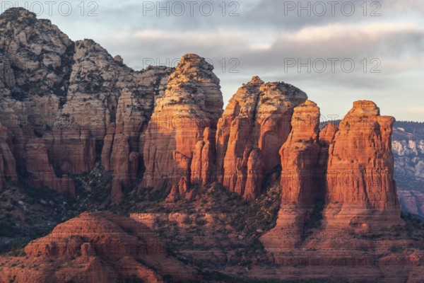 Towering red rock formations in a desert landscape with warm sunset lighting casting long shadows in Sedona, Arizona, USA, North America