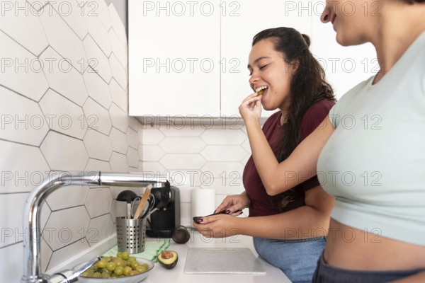 A cheerful lesbian couple shares a coffee break in their stylish kitchen. They enjoy a moment of laughter and connection, creating a relaxed, happy atmosphere