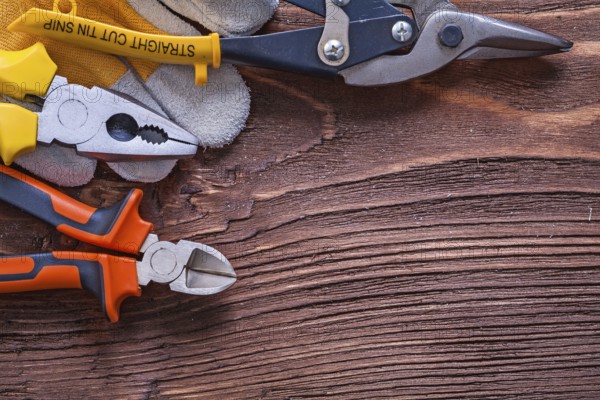 Nippers pliers wire-cutter and construction glove on wood board maintenance concept