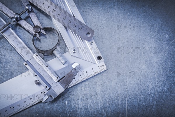 Metal ruler try square trammel caliper construction pair of compasses on metallic background
