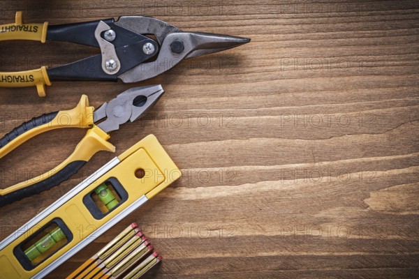 Pliers tin snips construction level wooden meter on wood board