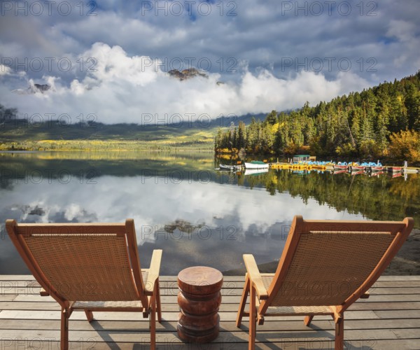 Pyramid Mountain reflected in Pyramid Lake. Two comfortable wooden sun beds for tourists, interconnected table