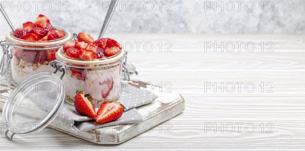 Parfait with Fresh Strawberries, Yoghurt and Crunchy Granola in Transparent Glass Mason Jars on White Rustic Wooden Background Angle View, Healthy Breakfast or Light Summer Dessert, Copy Space, food photography, food photography