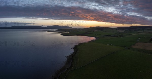 Sunset with cloud band on the coast of Scapa Flow with view to the island of Hoy, drone shot, Orphir, Orkney, Scotland, Great Britain