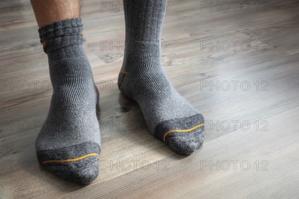 An image of male feet in grey socks on a wooden floor