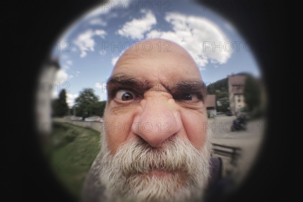 An image of an angry man looking to a peephole door