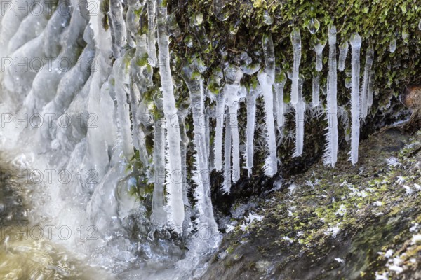 Frost and small icicles on a stone in the river. Spring thaw
