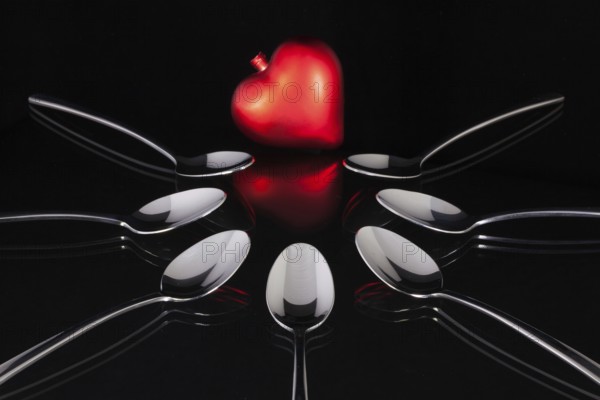 Teaspoons and love symbol on the black glass desk