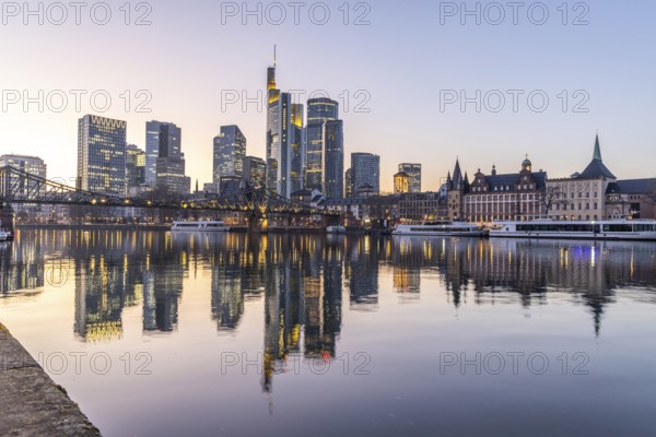 View over the river Main with a modern illuminated skyline in the background in the evening, at sunset. Beautiful overview of the city and its surroundings in Frankfurt, Hesse