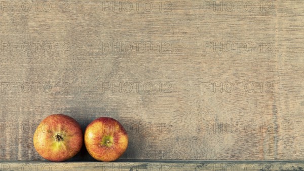 An image of a wooden background with two small apples
