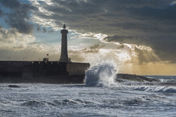 Scenic sunset over the atlantic ocean, a lighthouse at the shore of Morocco, waves break at the coast