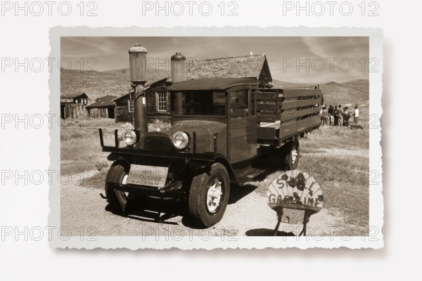 Old lorry at the petrol pump of the only petrol station in the former gold mining town of Bodie. Photo in sepia tone with white jagged edge and reclining shadow. Old-time truck at the gas pump of the only gas station of the former gold mining town of Bodie. Photo in sepia tone with white jagged edges in the character of old photos