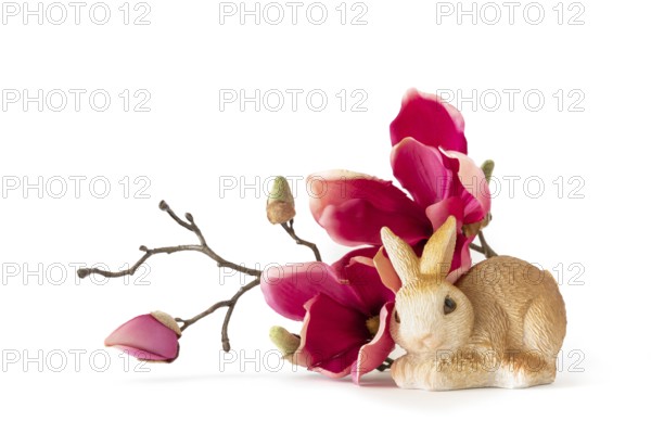 An image of an easter bunny sitting by some red magnolia flowers