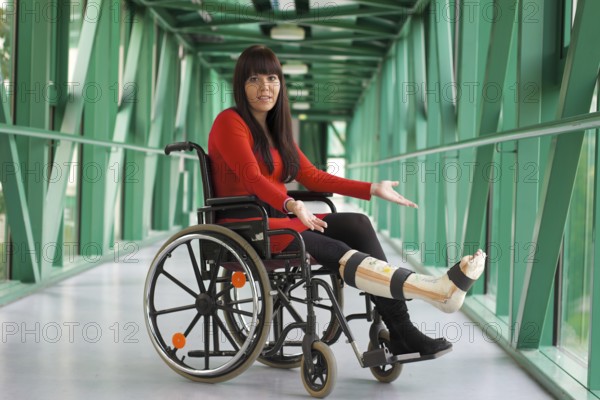 Young woman with plaster leg sits in a wheelchair Austria
