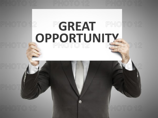 A business man holding a paper in front of his face with the text great opportunity