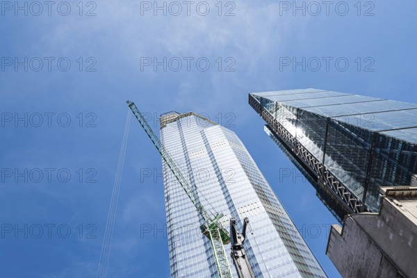 London, UK, May 14, 2019: Low angle view of skyscraper with cranes under construction in the City of London against blue sky with space for copy