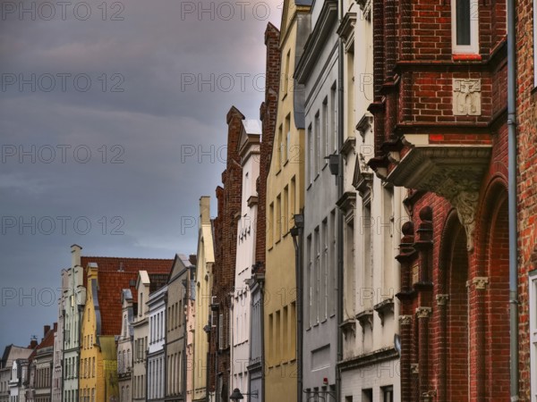 A row of historic red brick buildings under a cloudy sky, gothmund, travemünde, lübeck, germany