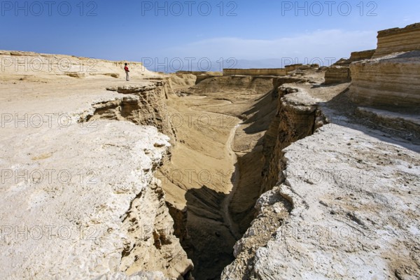 Woman tourist in a red sweater admires the landscape. The Judean Desert. Israel. Interesting walk among picturesque hills, cliffs and limestone gorges. Dead Sea